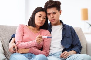 So You Had Unprotected Sex. When Can You Take A Pregnancy Test? 2 couple looking confused at a pregnancy test
